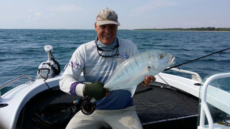 A golden trevally from deep water next to a tight pack of baitfish