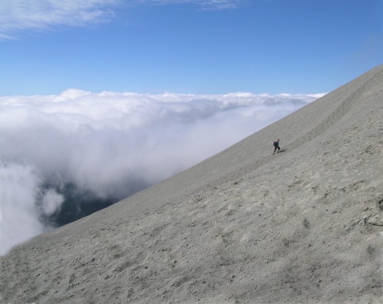 Mount Saint Helen. Lone hiker reaching clouds on the way to summit.